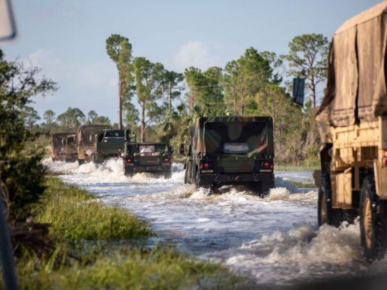 Florida National Guard vehicles mobilizing over a flooded road to provide aid for Hurricane Helene victims.